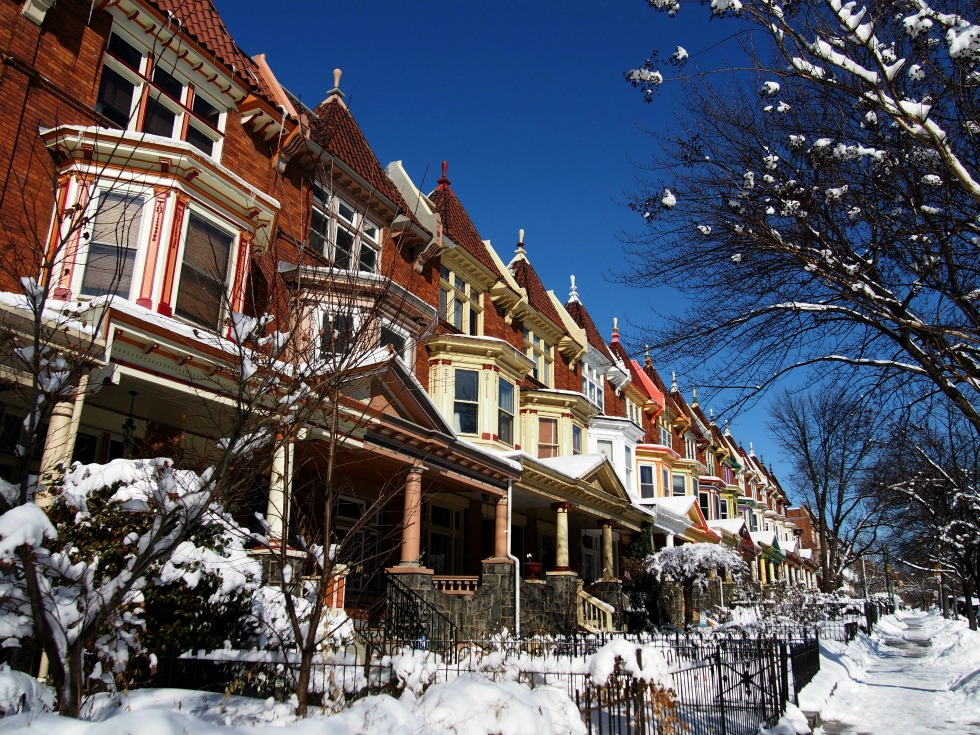 Rowhomes in Baltimore, Maryland on a sunny day, with the trees and sidewalks covered with snow.