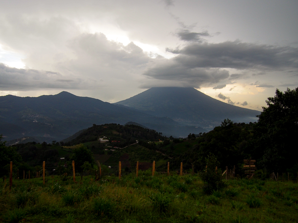 Clouds and a glimpse of the sunset behind a volcano seen on an overcast evening in Hobbitenango, near Antigua, Guatemala