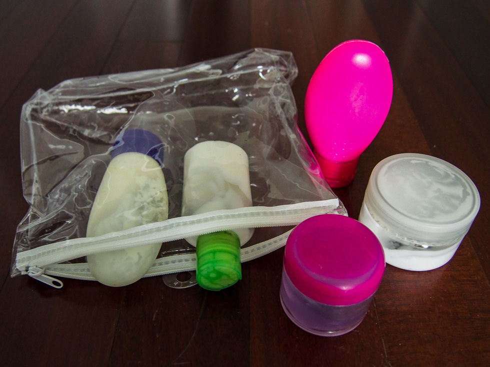 A TSA-approved bag for toiletries, with five small (less than 3 oz) containers of various colors