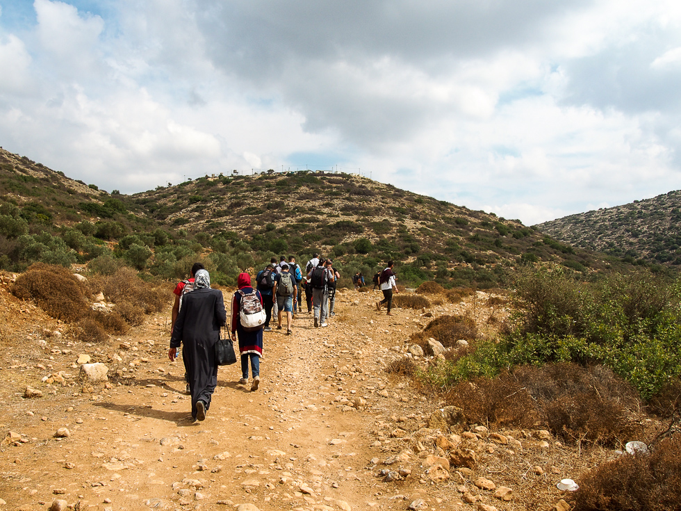 A group of Palestinian hikers (of all genders) walking through Wadi Qana in the West Bank of Palestine