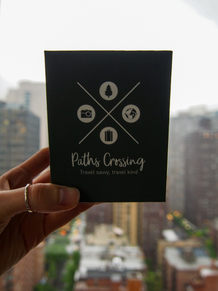 Box of Paths Crossing travel card game held against the backdrop of New York City