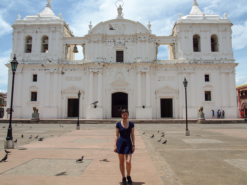 Solo female travel in Nicaragua: Alissa in a blue dress in front of Leon's cathedral on a sunny day