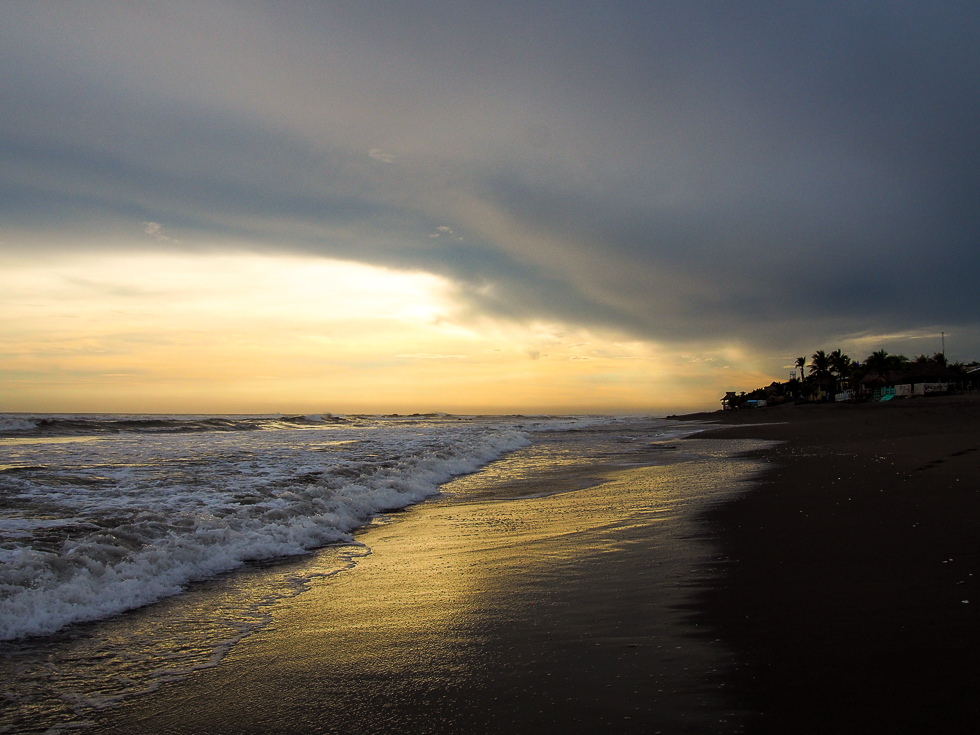 View of the Pacific Ocean and the setting sun under a canopy of dark clouds on the beach at Las Penitas, seen just two days after I got food poisoning while in Leon, Nicaragua