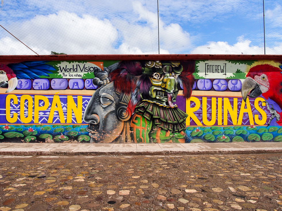 Colorful mural in Copan Ruinas, Honduras with the words "Copan Ruinas" written out among Mayan images and parrots