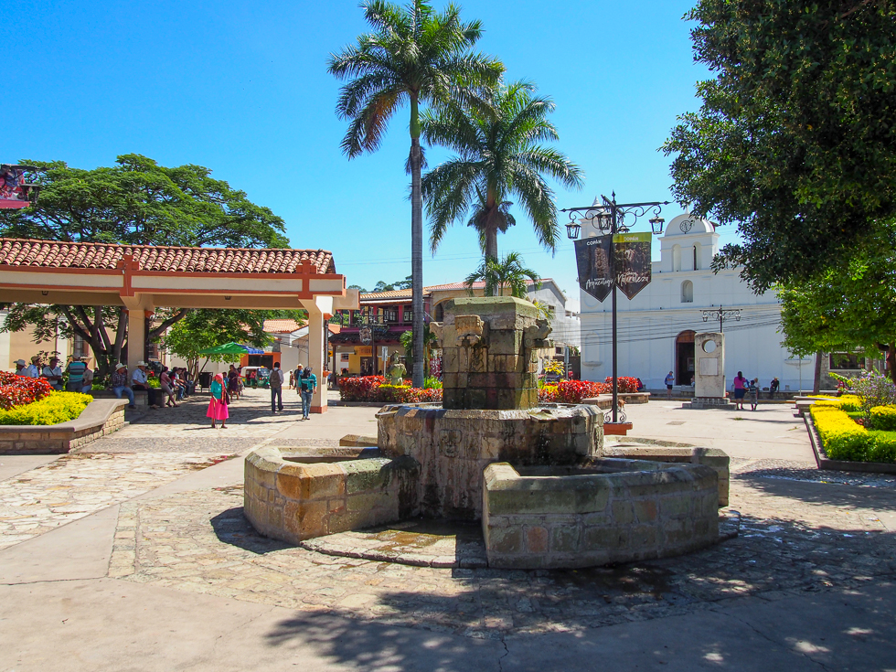 Central Park in Copan Ruinas, Honduras, with a fountain in the foreground and a small, white church in the background