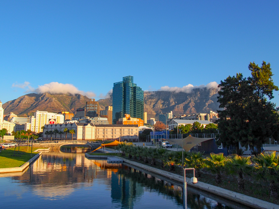 Shot of a small waterway, some building in the Cape Town skyline, and Table Mountain in the distance in Cape Town, South Africa, a place that recently experienced a major water crisis