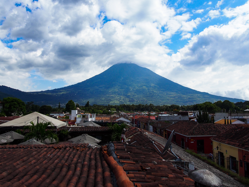 View of the Water Volcano from a rooftop in Antigua, Guatemala, with houses and roofs in the foreground